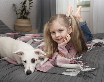 Portrait of happy girl with dog on bed at home