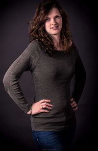 Portrait of young woman standing against black background