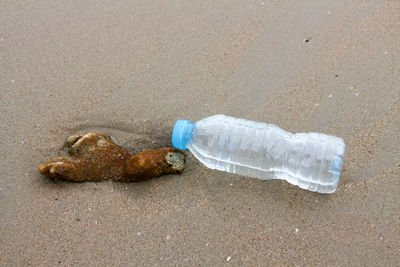 Garbage bottle on sand at beach