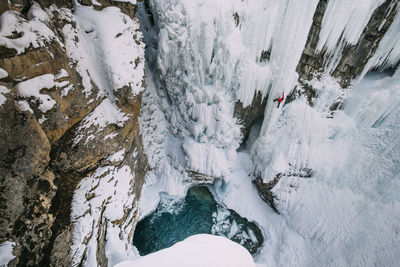 High angle view of woman climbing on snowcapped mountain during winter