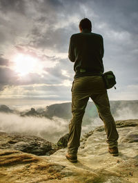 Photographer on cliff with camera viewfinder in his face. nature photographer takes photos on peak