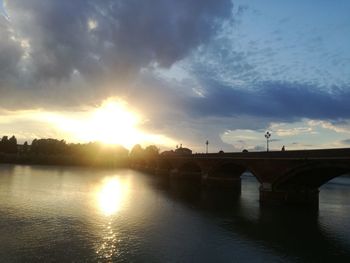 Bridge over river against sky during sunset