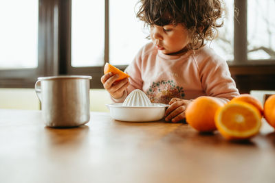 Cute girl holding orange at home