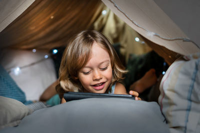 Happy cute little boy playing in a teepee tent at home.