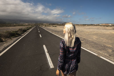 Rear view of woman standing on road against sky