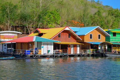 Houses by river against buildings