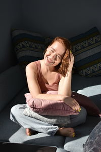 Portrait of a smiling young woman sitting on sofa