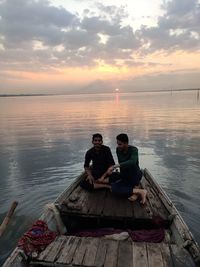 High angle view of men sitting on boat in lake against sky