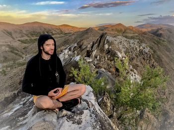 Young woman meditation while sitting on rock against mountains