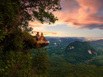 Rear view of man standing on mountain against sky during sunset