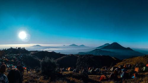 Group of people on mountain range against blue sky