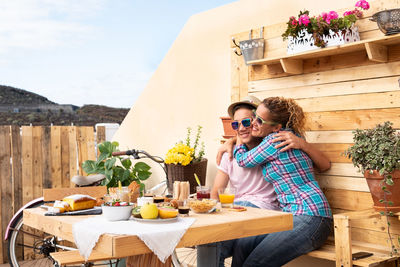 Happy mother embracing son on breakfast table at terrace