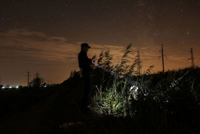 Silhouette man standing on field against sky at night