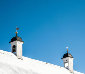 Low angle view of lighthouse against building against clear blue sky