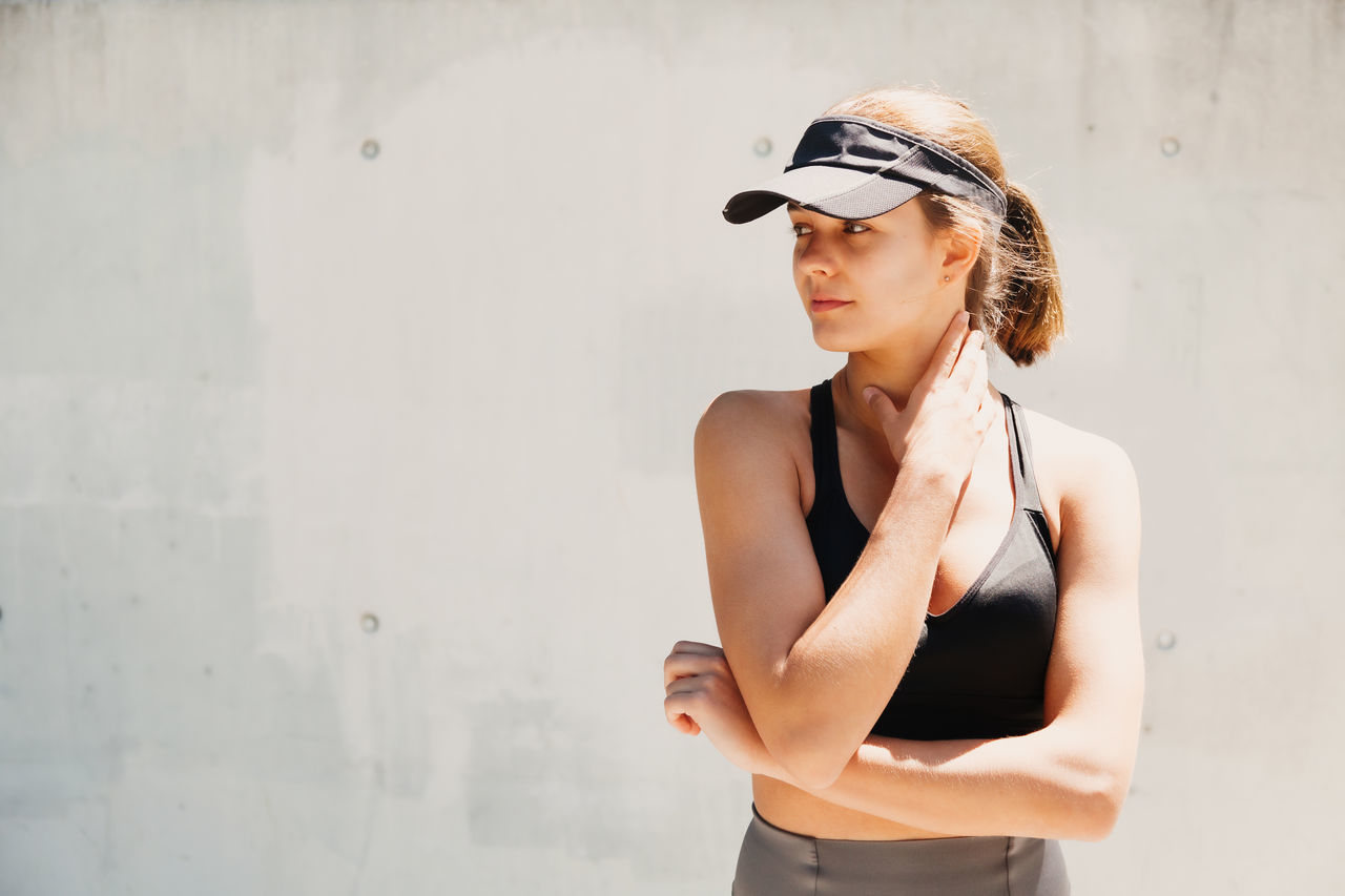 WOMAN LOOKING AWAY WHILE STANDING AGAINST WALL