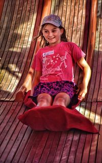 Smiling girl sitting on wooden slide