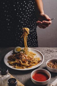 Midsection of woman eating food in bowl on table