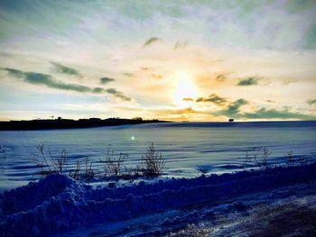 Scenic view of frozen lake against sky during sunset