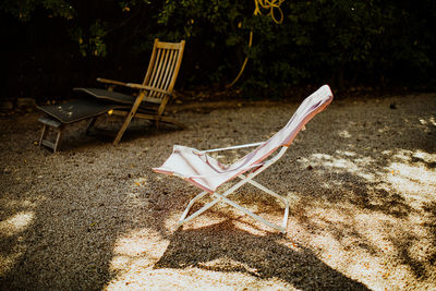 Empty lounge chairs on sand in park