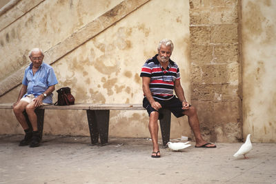 Portrait of friends sitting on wall