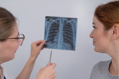 Side view of young woman looking away against wall