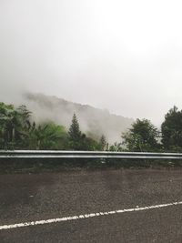 Mountain road by trees against sky