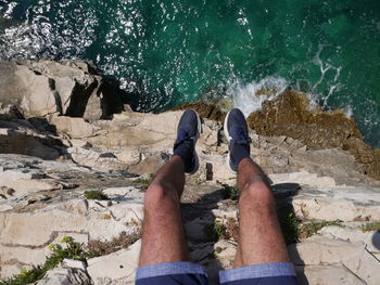 Low section of man on rock at sea shore