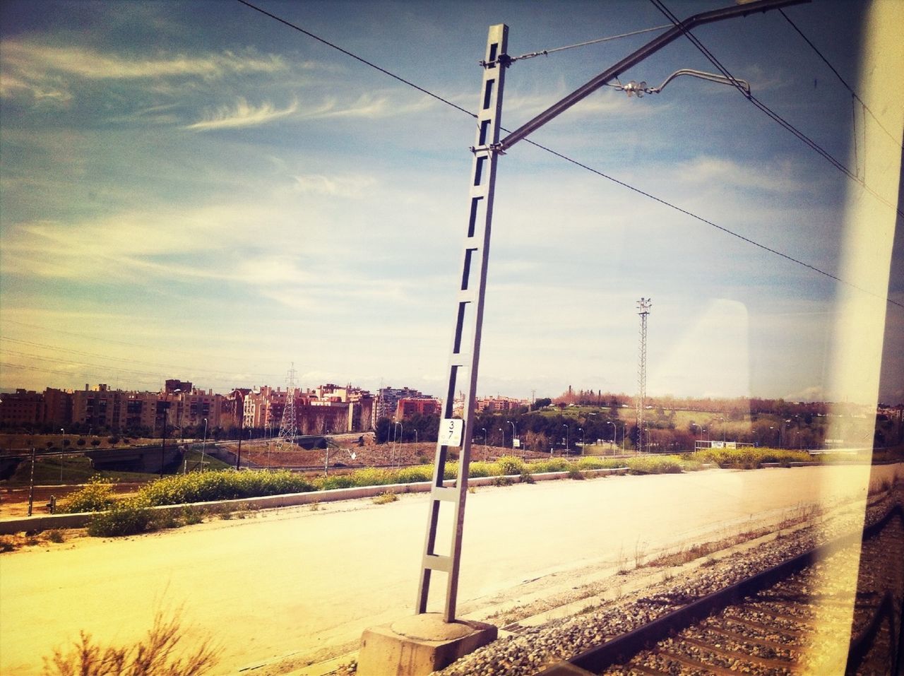 sky, built structure, power line, transportation, electricity pylon, cloud - sky, building exterior, architecture, water, cloud, city, road, no people, connection, power supply, street, railroad track, cable, outdoors, electricity