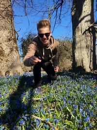 Portrait of man kneeling on liverwort flowers field in sunny day