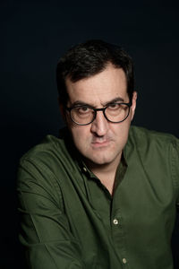 Portrait of man wearing eyeglasses against black background