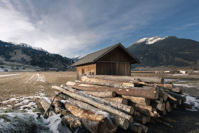 Logs on field against sky during winter