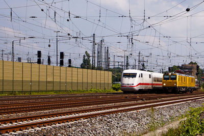 Modern train by cables against sky