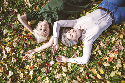 Carefree women smiling while lying on grass at park