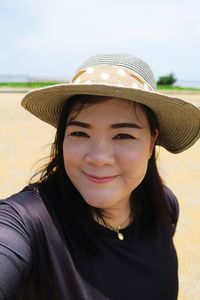 Portrait of smiling mid adult woman wearing hat standing against sky during sunny day