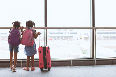 Rear view of siblings standing at airport