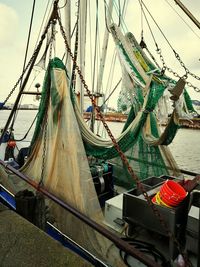 Fishing boat moored at harbor against sky