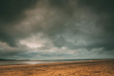 Scenic view of beach against cloudy sky