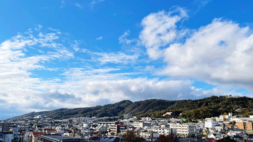 Townscape by mountains against blue sky
