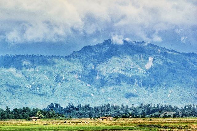 landscape, field, tranquil scene, grass, scenics, tranquility, beauty in nature, sky, mountain, nature, rural scene, non-urban scene, agriculture, grassy, cloud - sky, mountain range, idyllic, weather, remote, green color