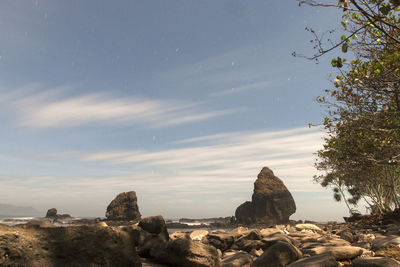 Rock formations on beach against sky