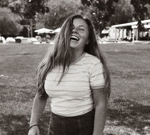 Young woman laughing while standing on land in park