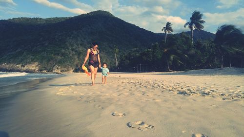 Full length of young woman on beach against sky