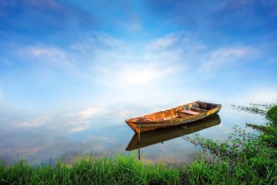 Abandoned boat moored in water against sky