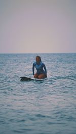 Woman surfing in sea against sky