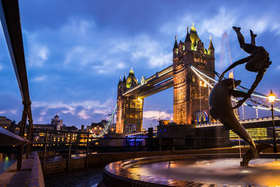 Illuminated tower bridge against cloudy sky