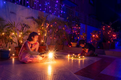Rear view of woman sitting on street at night