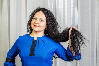 Portrait of smiling woman standing against wall