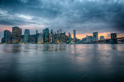River by buildings against sky at dusk
