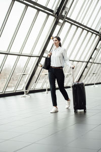 Businesswoman with suitcase walking in corridor of office