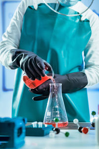 Midsection of female scientist experimenting in laboratory